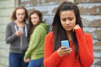 A woman reads her cell phone while others look in the background