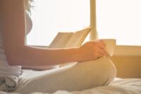 A woman reads a book while holding a cup of coffee