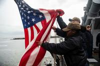 An Operations Specialists Seaman lowers the national ensign aboard the USS Vella Gulf.