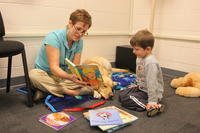 young child and adult reading to a dog