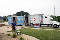 Movers pack a military members property into boxes and load it into crates.