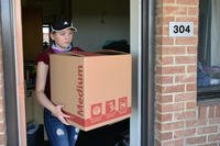 woman carrying a box out of a house