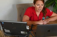 woman sitting at kitchen table working on computers