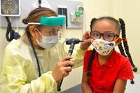 Navy doctor checks the ears of five-year-old.