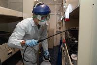 A sailor disinfects a berthing aboard the aircraft carrier Theodore Roosevelt