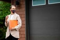 Realtor with paperwork and keys outside a home