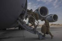 Aircrew carry their gear into a C-17 Globemaster III.