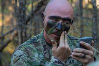 Soldier in the 95th Civil Affairs Brigade applies camouflage.