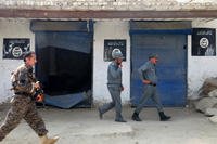 InAfghan police walk past Islamic State militant flags.