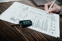 Person filling out finance paperwork while buying a car