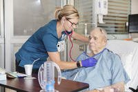 Patient checked by nurse as he recuperates from open-heart surgery.