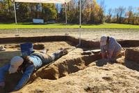 Jane C. Skinner and Samantha Muscella excavate post holes at the bottom of a stockade trench