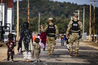 U.S. Military Police walk past Afghan refugees at Ft. McCoy.