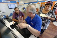 Alan Leafman, center, president of Health Insurance Express Inc., helps Raquel and John Bernal of Apache Junction, Ariz., navigate the nation's health-care insurance system online at the Health Insurance Express store in Mesa, Ariz.