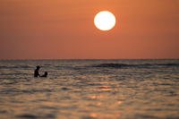 Swimmers float in the Pacific Ocean as the sun sets off Waikiki Beach in Honolulu. 