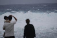 Family members watch waves affected by a severe weather system in Itoman, southern Japan