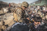A U.S. Marine with Joint Task Force-Crisis Response assists evacuees at an evacuation control checkpoint (ECC) during an evacuation at Hamid Karzai International Airport, Kabul, Afghanistan.