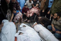 Palestinians mourn over the bodies of their relatives who were killed in Israeli bombardments
