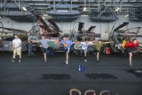 Sailors perform a stretching exercise in the hangar bay of the aircraft carrier USS Harry S. Truman (CVN 75).