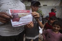 Palestinians hold leaflets dropped by Israeli planes calling on them to evacuate ahead of an Israeli military operation