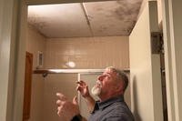 A lead mold remediation specialist at Fort Stewart shows where a barrack room's bathroom ceiling has mold.