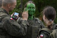 Volunteers in Poland's army learn to apply camouflage face paint during basic training in Nowogrod