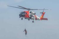 A U.S. Coast Guard rescue swimmer rappels over the water