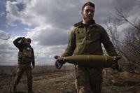 Ukrainian soldiers carry shells to fire at Russian positions on the front line