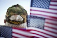 A man wears a veterans hat surrounded by flags as he attends a Veterans Day parade Tuesday in Montgomery, Ala.