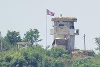 A North Korean soldier stands at the North's military guard post as a North Korean flag flutters in the wind, seen from Paju
