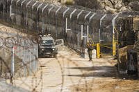 An Israeli soldier stands guard at a security fence gate near the so-called Alpha Line