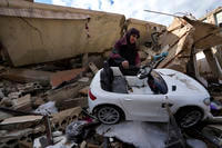 Mariam Kourani removes a toy car from the rubble of her destroyed house.