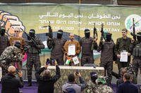 Israeli captives are escorted by Hamas fighters on a stage