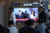 People pass by a TV screen reporting North Korea confirms troops deployment to Russia