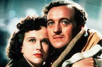 June (Kim Hunter) and Peter (David Niven) stand against the judge, jury and trial members.