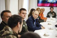 Russian President Vladimir Putin, center, speaks with volunteers in the Kursk region