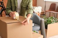 A woman's arms appear taping a box closed.