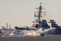 A Philadelphia Fire Department fire boat streams water as the USS Lassen passes by at the start of the 250th anniversary of the U.S. Navy and Marine Corps, Parade of Ships, as seen from Navy Yard, south Philadelphia.