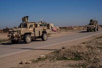 A U.S. military convoy drives along a road in Syria.
