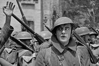 John Gilbert as World War I soldier Jim Apperson marches with a column of helmeted troops in The Big Parade (1925), looking anxiously to the side.