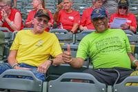 Two veterans smile while sitting in the stands of a baseball field.