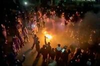 Protesters dancing and cheering around a bonfire.