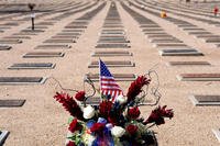 A flag and flowers adorn a grave at the National Memorial Cemetery of Arizona on Veterans Day, Tuesday, Nov. 11, 2025, in Phoenix. (AP Photo/Ross D. Franklin)