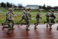 Medics in Army uniforms run on a track.