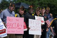 Veterans hold signs supporting the PACT Act.