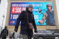 People walk past an advertising screen promoting contract military service in the Russian army's unmanned systems units, during a snowfall in St. Petersburg, Russia, Friday, Feb. 20, 2026. (AP Photo/Dmitri Lovetsky)
