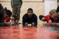 A Marine recruiter with a mustache and long-haired Marine recruits do planks.