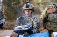 Soldier with two trays outdoors in a breakfast line.