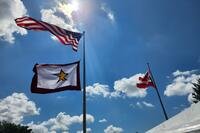 Three flags against the sky, one with a gold star.