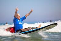 A veteran celebrates while adaptive surfing.